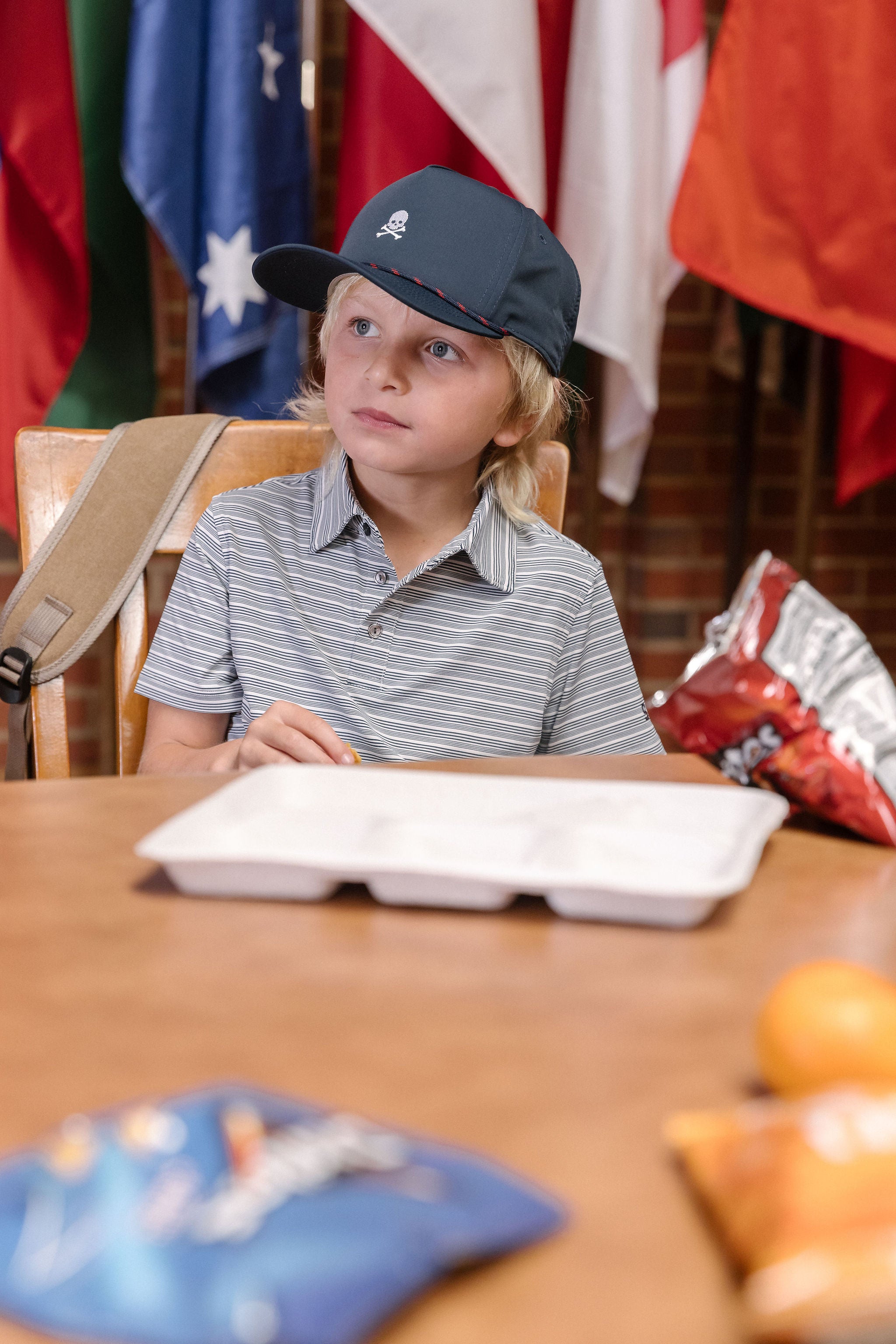 Child sitting at a table with a tray, surrounded by flags in the background