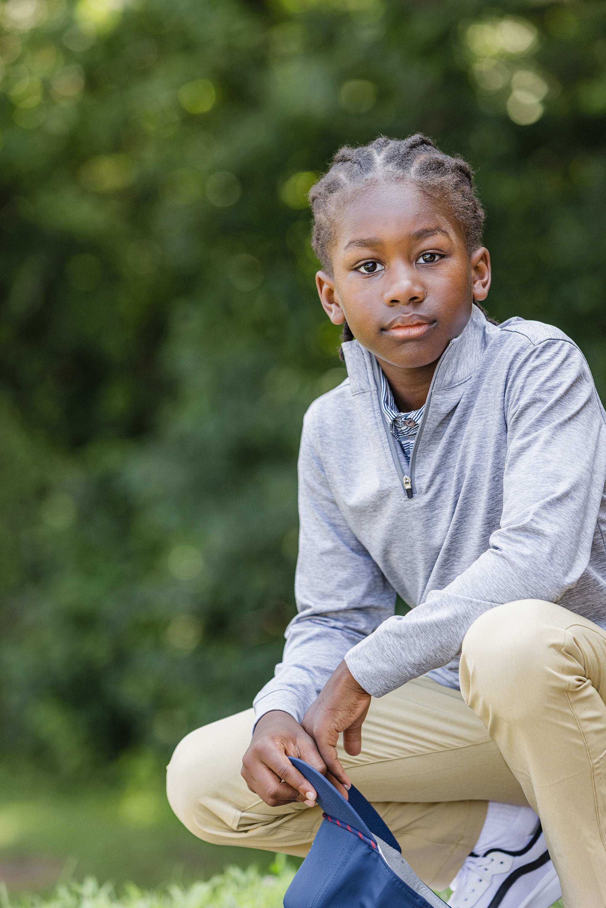 Child sitting outdoors with a blurred green background