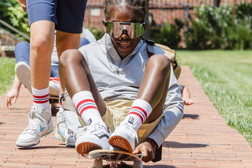 Two children riding skateboard on a brick path in a park