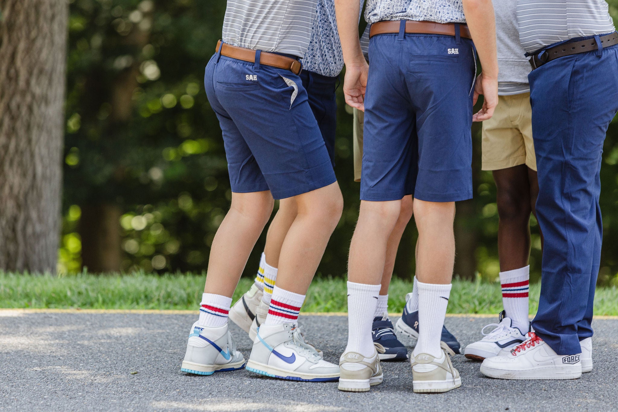 Group of kids wearing nike shoes with crew socks, navy shorts and pants, and patterned polos from Study Hall Kids.