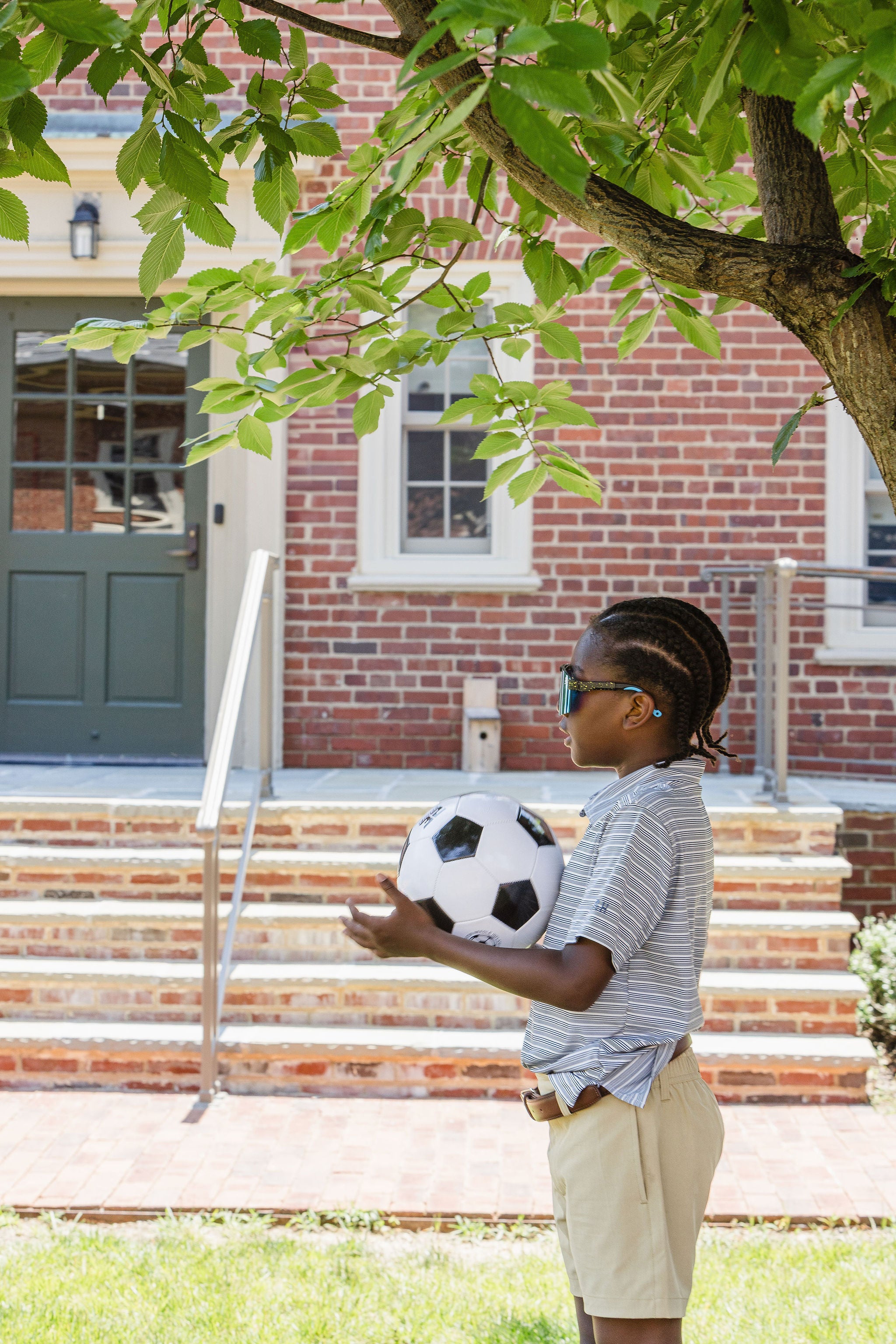 Young boy holding soccer ball in front of brick school steps