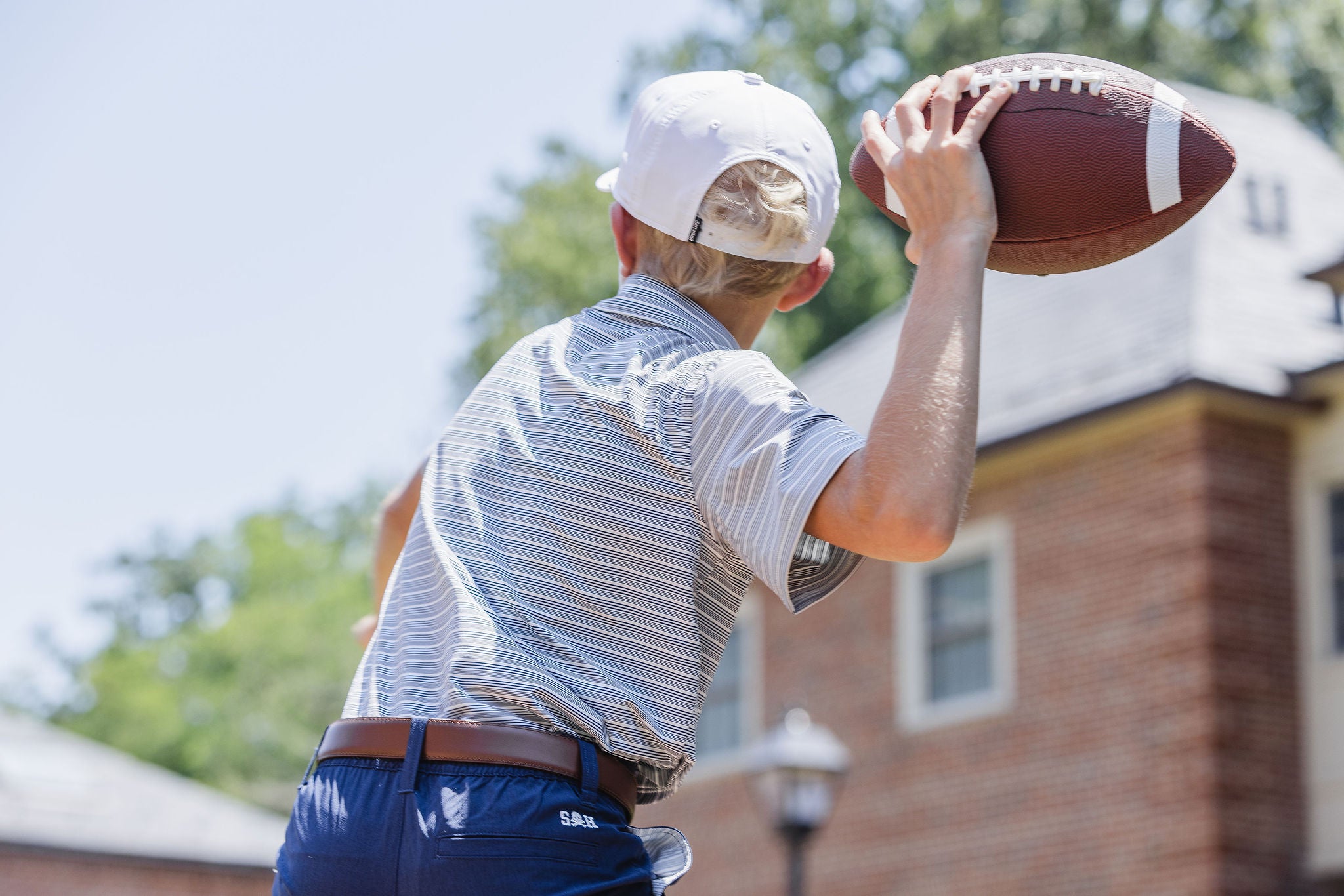 Person holding a football outdoors with a building in the background