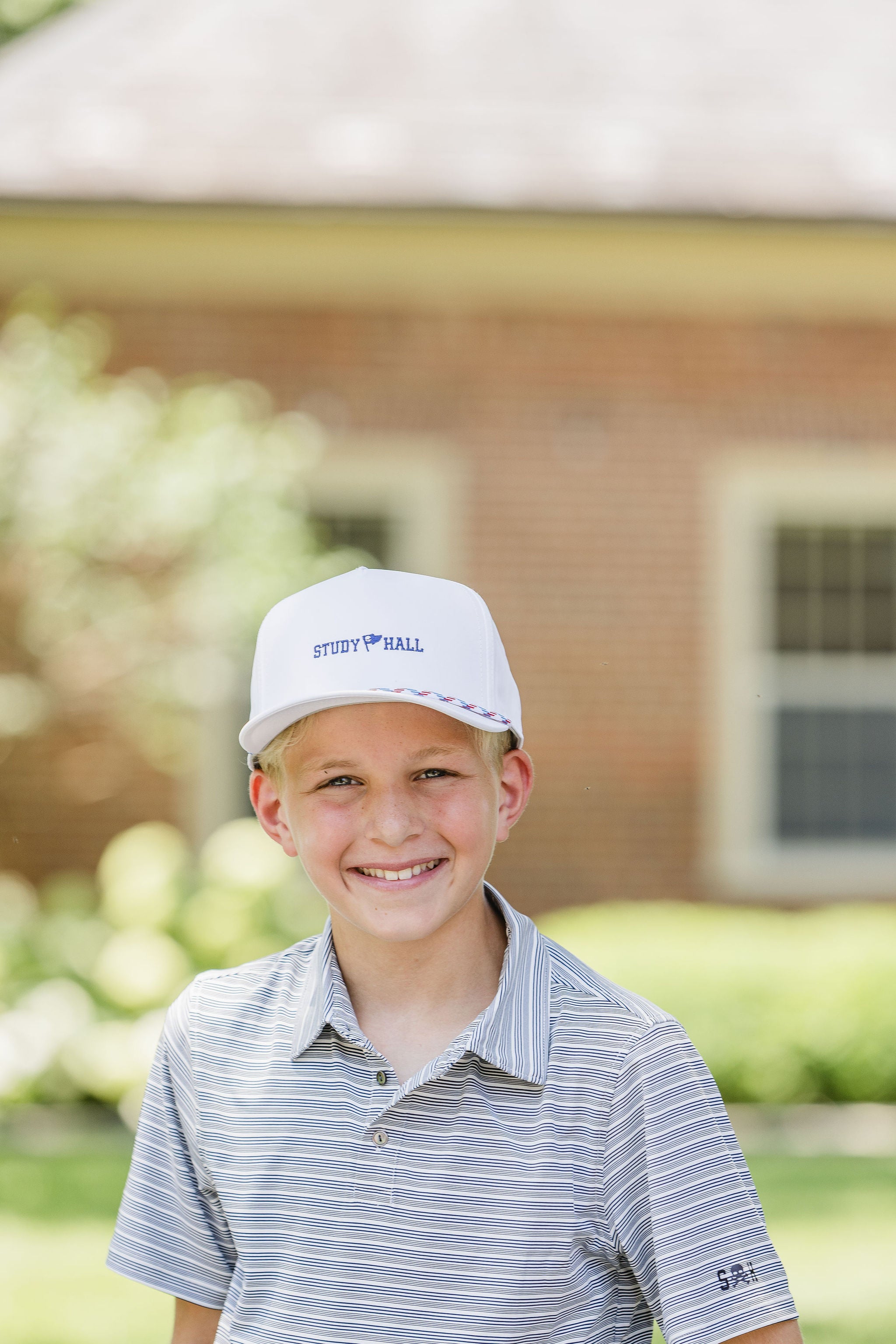 Young boy wearing a cap and striped shirt outdoors with a blurred background